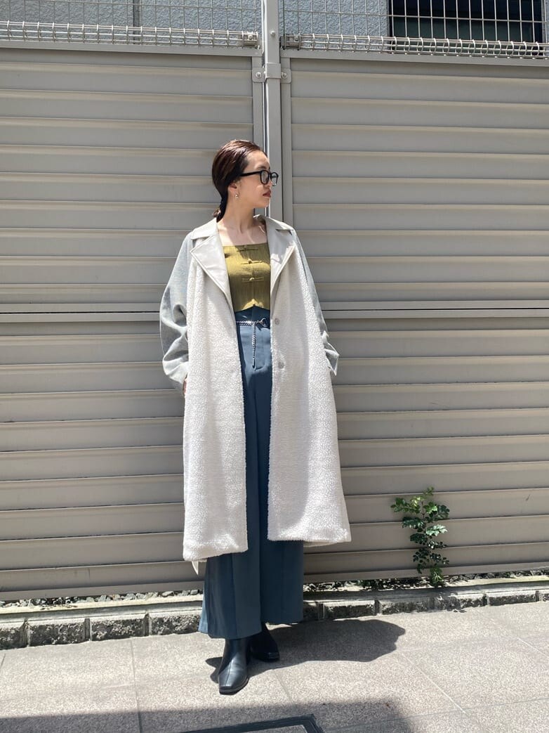 イエロー系のニット/セーター、ホワイト系のチェスターコート、ブルー系のスラックスを着用したレディースの秋コーディネートの3枚目の写真