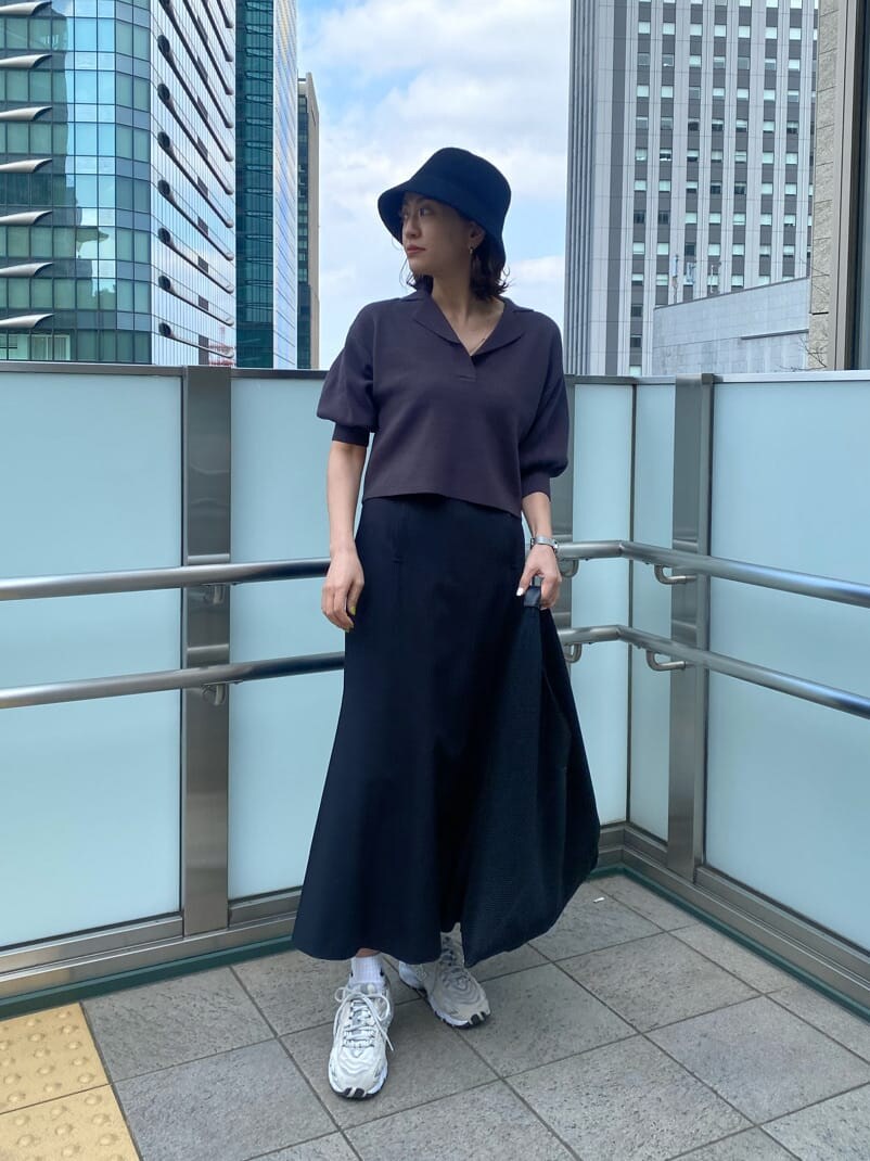 ブラック系のスカート、グレー系のニット/セーター、ブラック系のハットを着用したレディースの春コーディネートの2枚目の写真