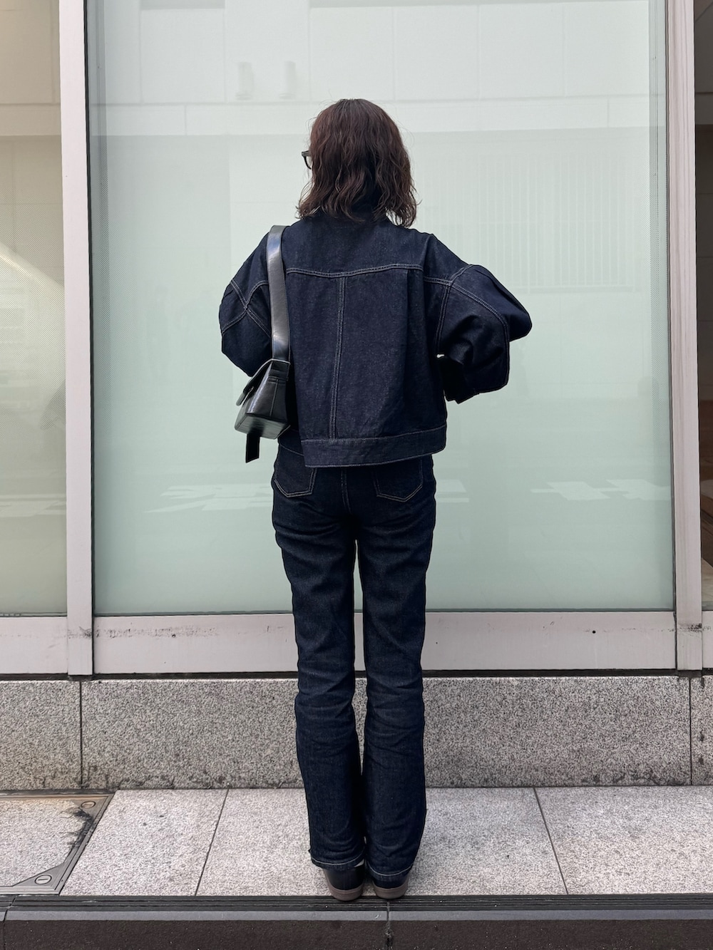 ブルー系のデニムジャケット、ブラック系のショルダーバッグ、ブルー系のデニムパンツを着用したレディースの春コーディネートの3枚目の写真
