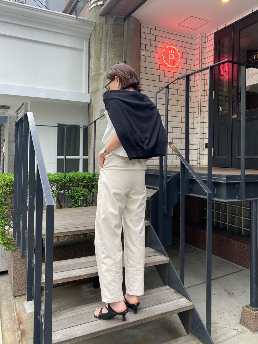 ブラック系のサンダル、ホワイト系のタンクトップ、ホワイト系のスラックスを着用したレディースの夏コーディネートの3枚目の写真