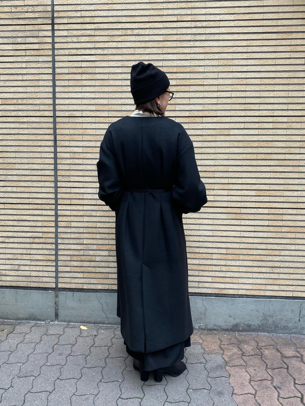 ブラック系のノーカラーコート、ブラック系のブーツを着用したレディースの冬コーディネートの4枚目の写真