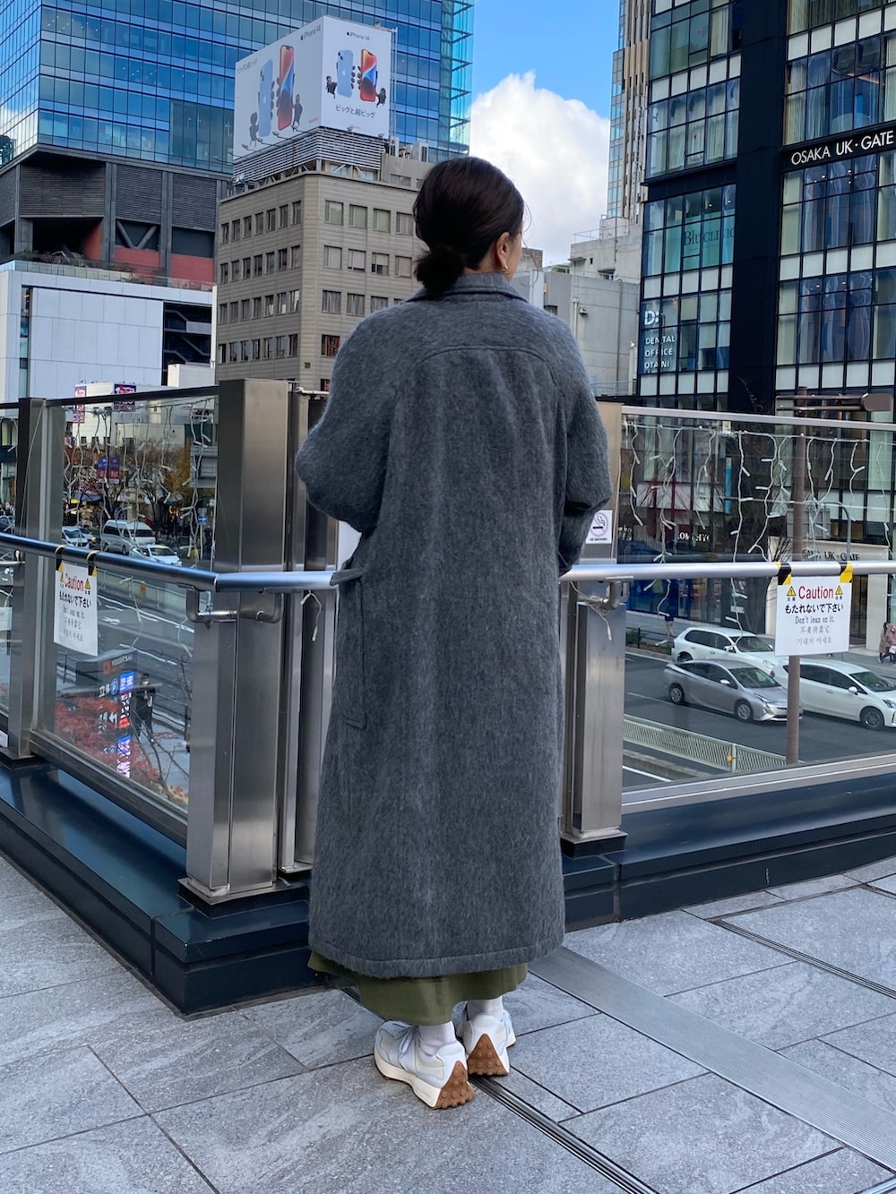 グレー系のチェスターコート、ホワイト系のニット/セーター、ベージュ系のスカートを着用したレディースの冬コーディネートの3枚目の写真