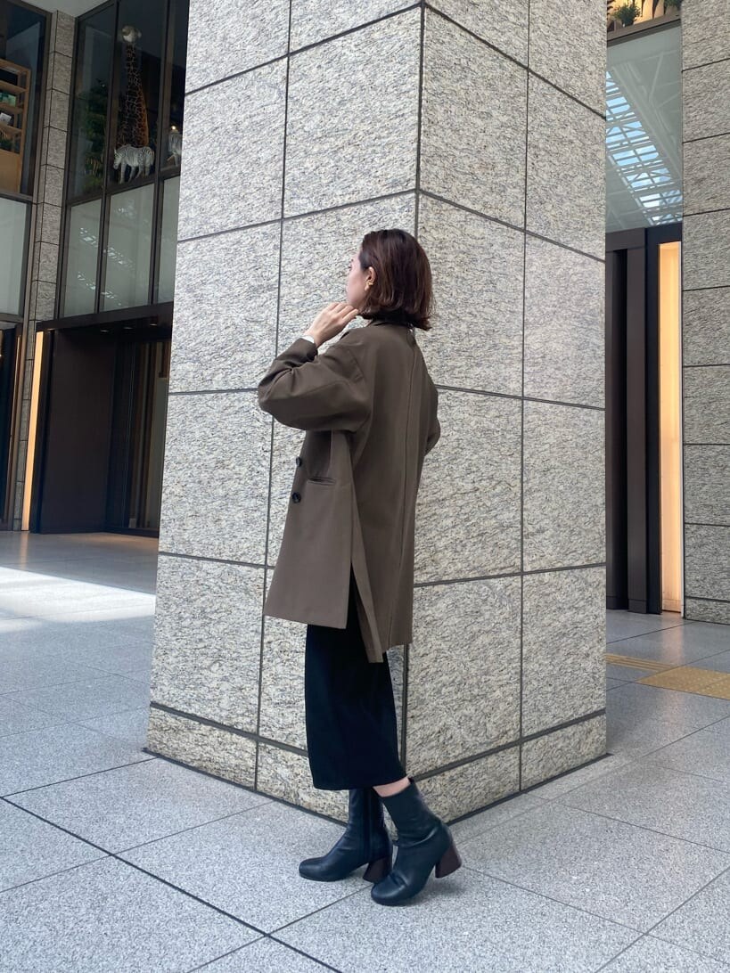 ブラック系のニット/セーター、ブラック系のスカート、ベージュ系のテーラードジャケットを着用したレディースの秋コーディネートの3枚目の写真