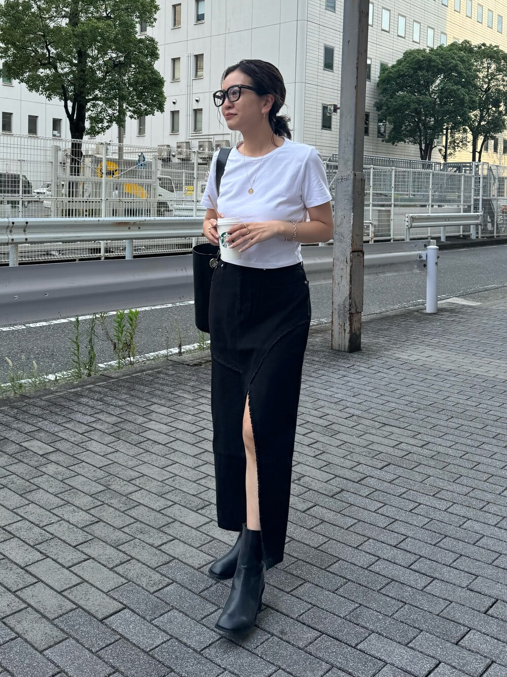 ブラック系のデニムスカート、ブラック系のブーツを着用したレディースの夏コーディネートの4枚目の写真