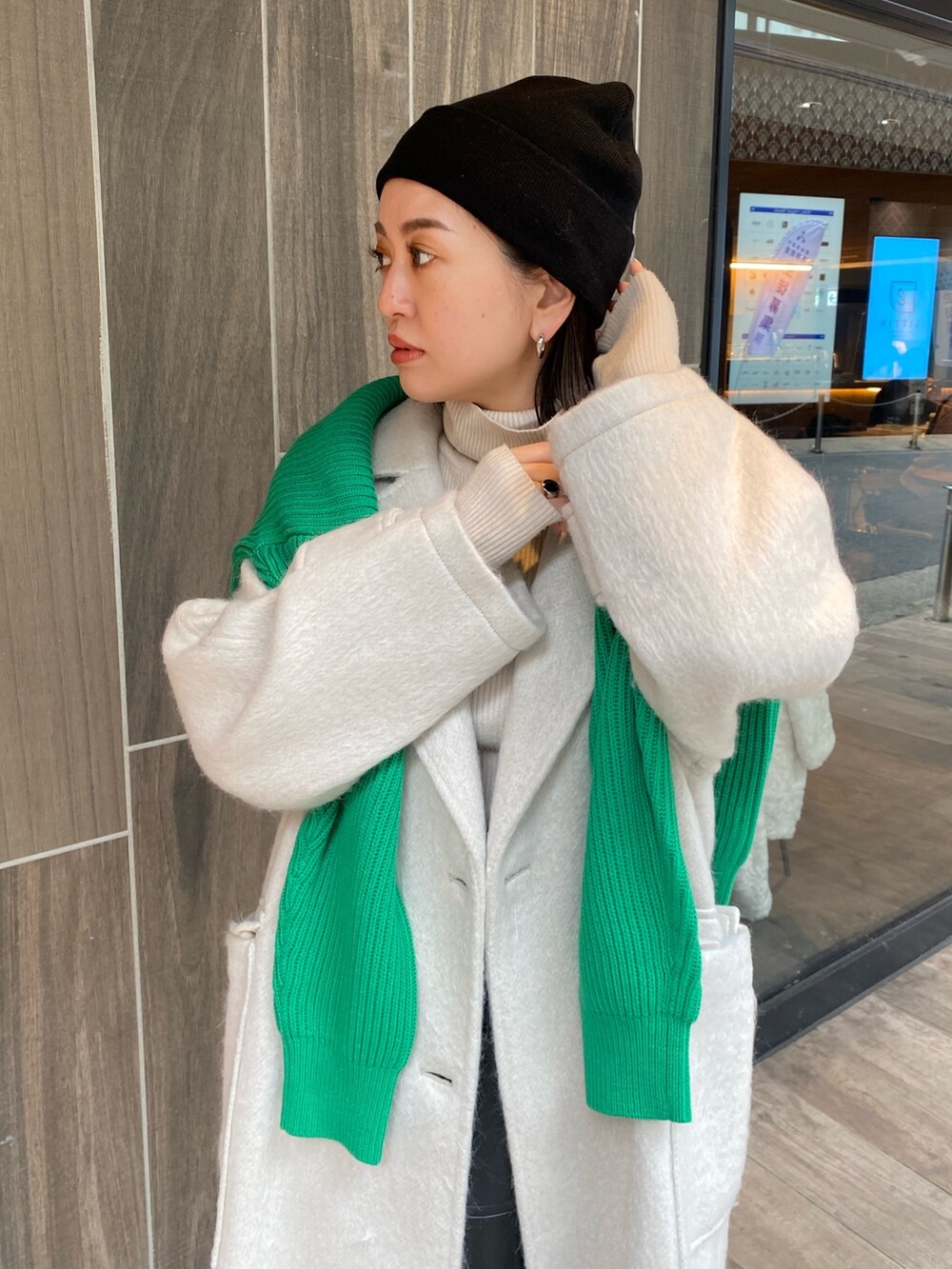 グリーン系のニット/セーター、ホワイト系のチェスターコート、ホワイト系のニット/セーターを着用したレディースの冬コーディネートの5枚目の写真