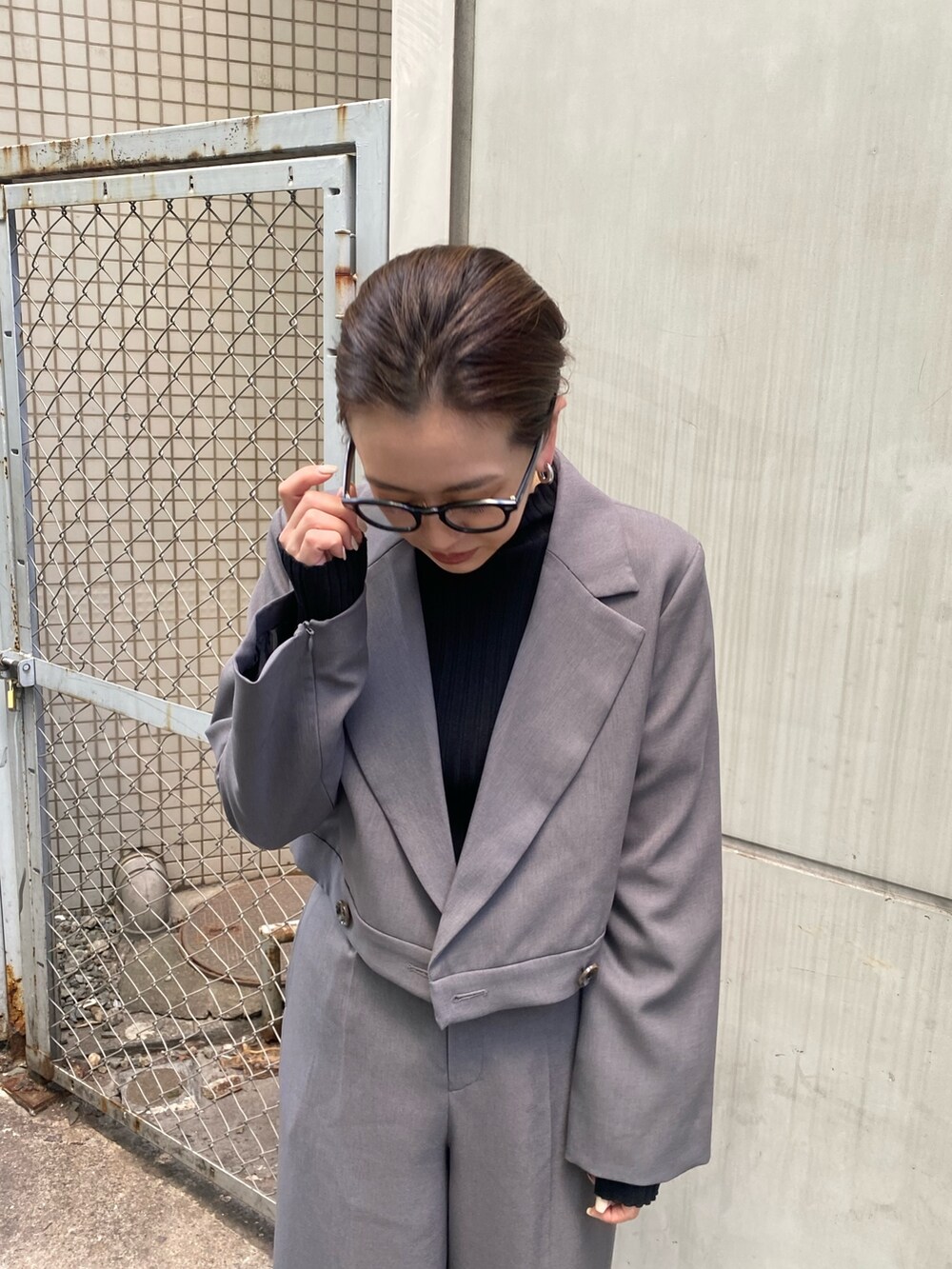 グレー系のテーラードジャケット、ブラック系のニット/セーター、グレー系のスラックスを着用したレディースの冬コーディネートの6枚目の写真