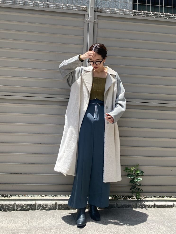 イエロー系のニット/セーター、ホワイト系のチェスターコート、ブルー系のスラックスを着用したレディースの秋コーディネートの2枚目の写真