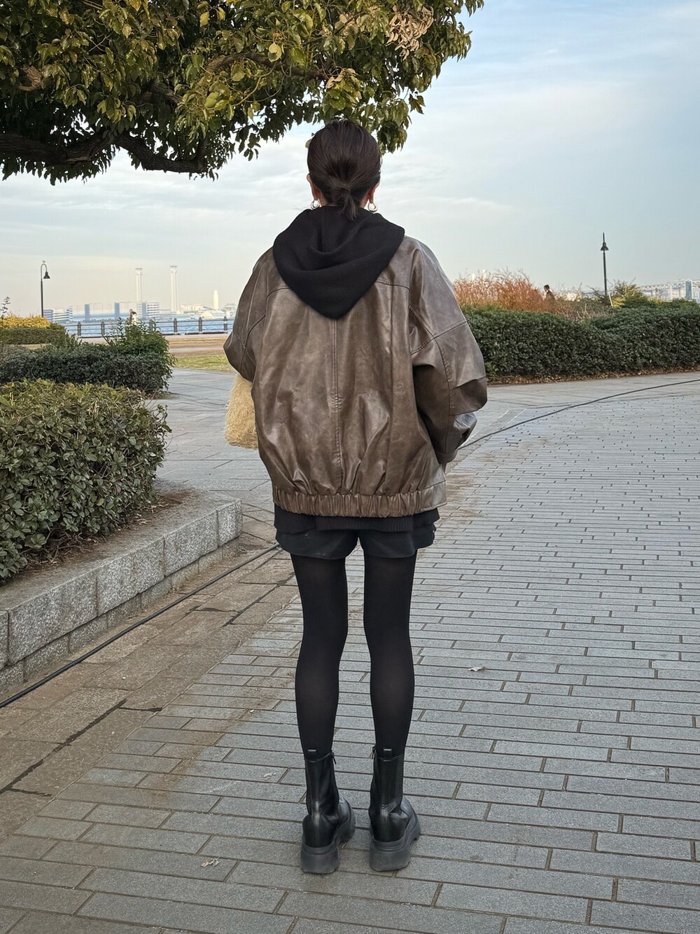 ブラウン系のブルゾン、ブラック系のブーツを着用したレディースの冬コーディネートの4枚目の写真