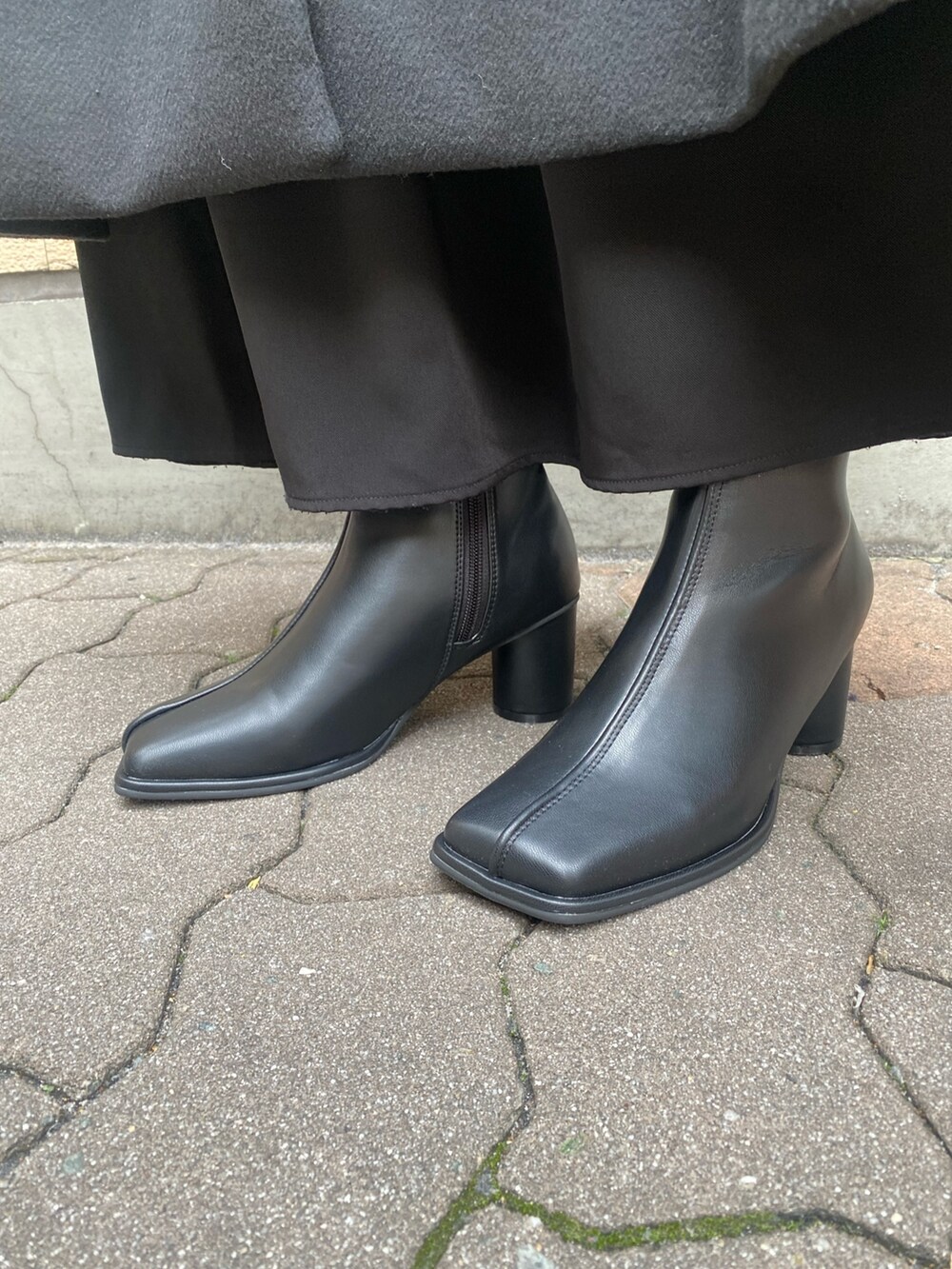 ブラック系のノーカラーコート、ブラック系のブーツを着用したレディースの冬コーディネートの6枚目の写真