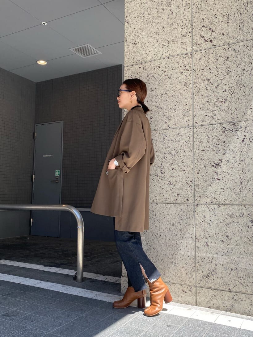 ベージュ系のテーラードジャケット、ブラック系のニット/セーター、ブラック系のデニムパンツを着用したレディースの秋コーディネートの2枚目の写真