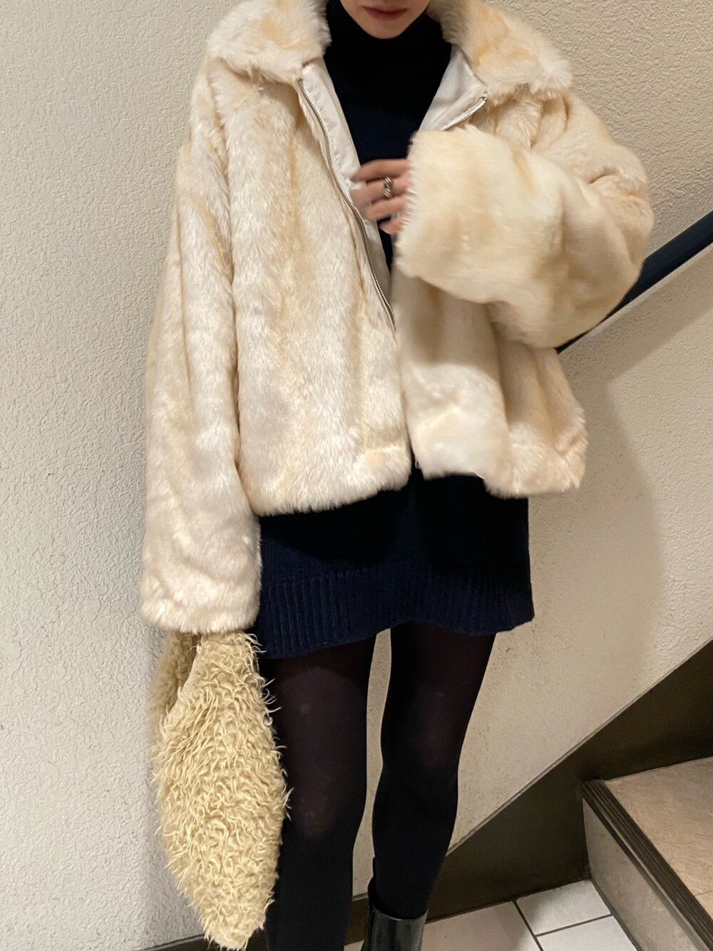 ホワイト系のブルゾン、ブラック系のブーツを着用したレディースの冬コーディネートの8枚目の写真