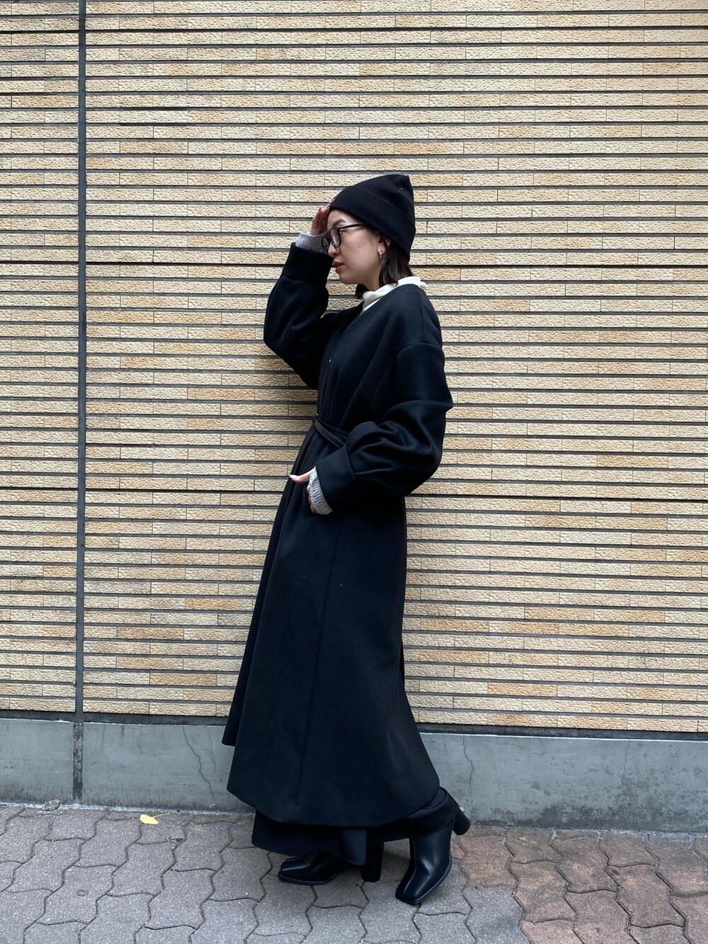 ブラック系のノーカラーコート、ブラック系のブーツを着用したレディースの冬コーディネートの2枚目の写真