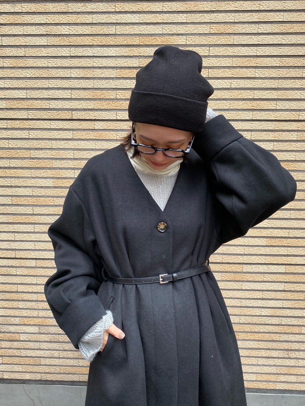 ブラック系のノーカラーコート、ブラック系のブーツを着用したレディースの冬コーディネートの5枚目の写真