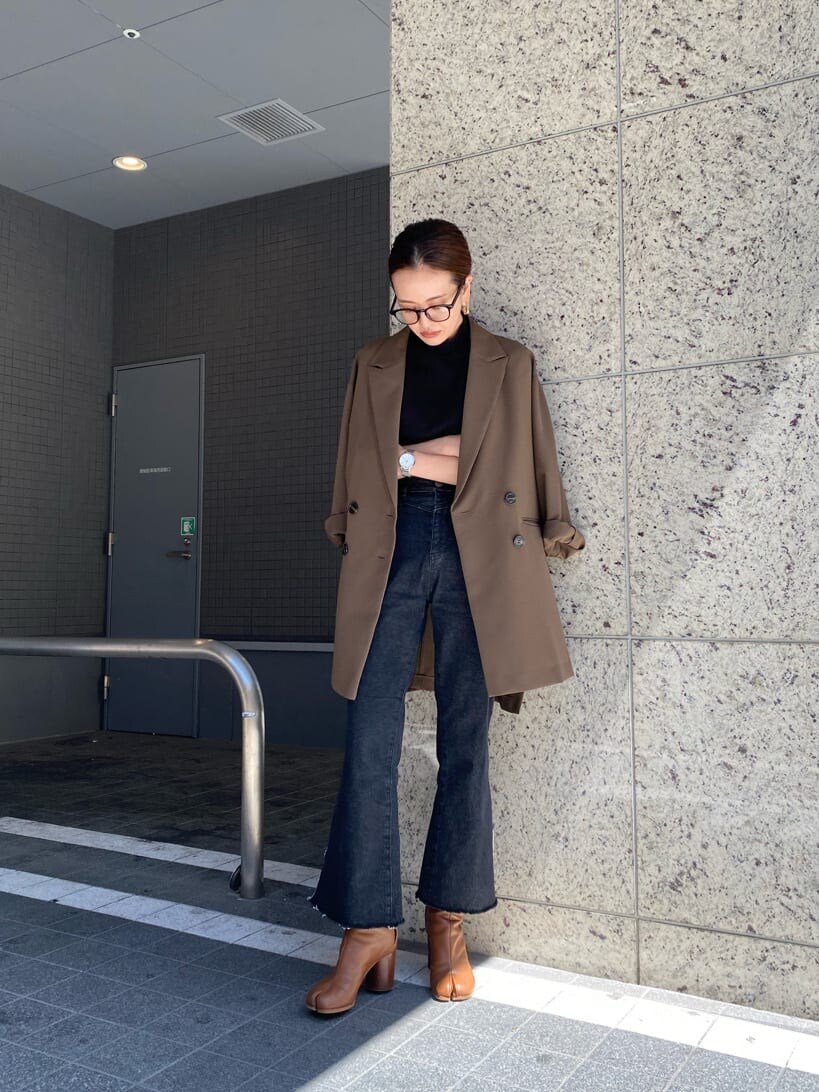 ベージュ系のテーラードジャケット、ブラック系のニット/セーター、ブラック系のデニムパンツを着用したレディースの秋コーディネートの6枚目の写真