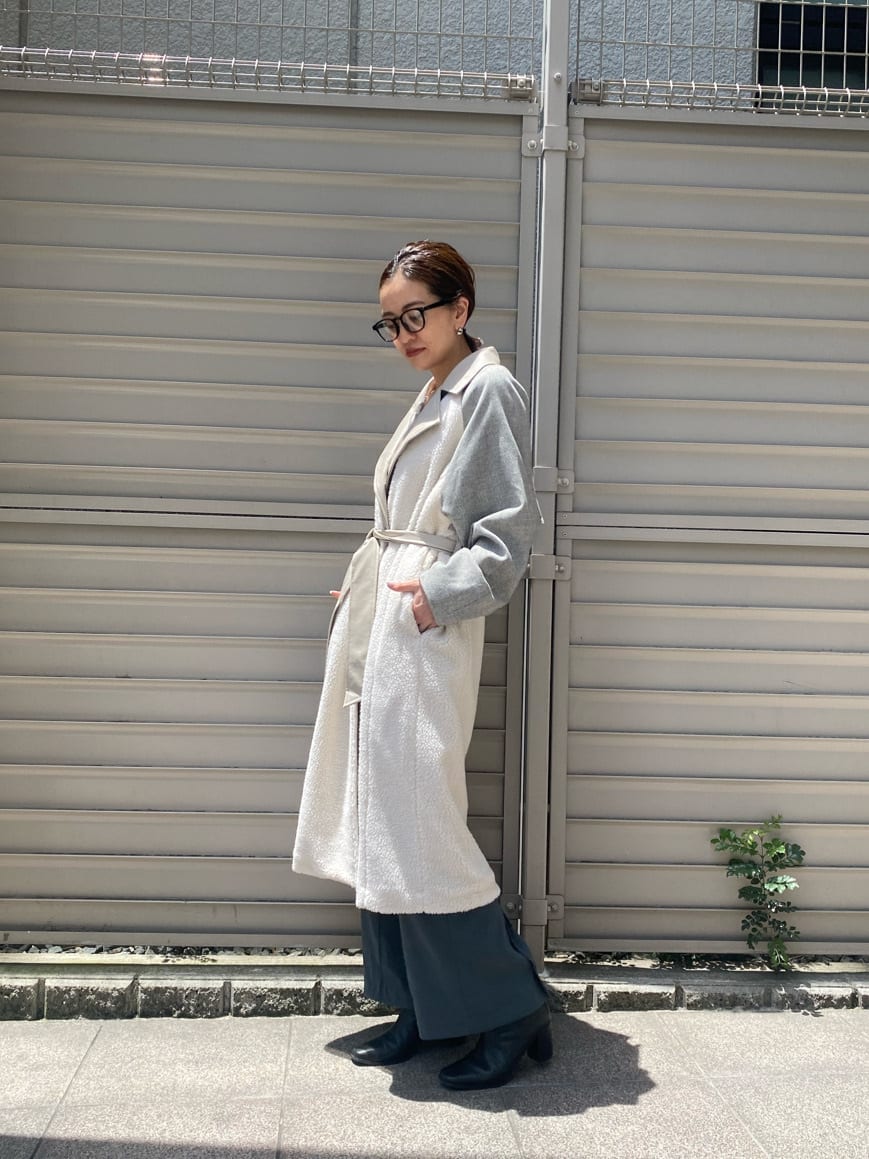 イエロー系のニット/セーター、ホワイト系のチェスターコート、ブルー系のスラックスを着用したレディースの秋コーディネートの4枚目の写真