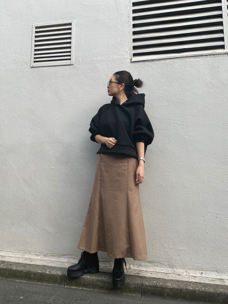 ブラック系のブーツ、ブラック系のパーカー、ブラウン系のスカートを着用したレディースの秋コーディネートの3枚目の写真