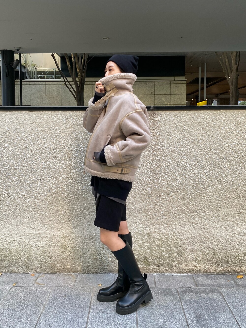 ベージュ系のムートンコート、ブラック系のニット/セーター、ブラック系のブーツを着用したレディースの秋コーディネートの5枚目の写真