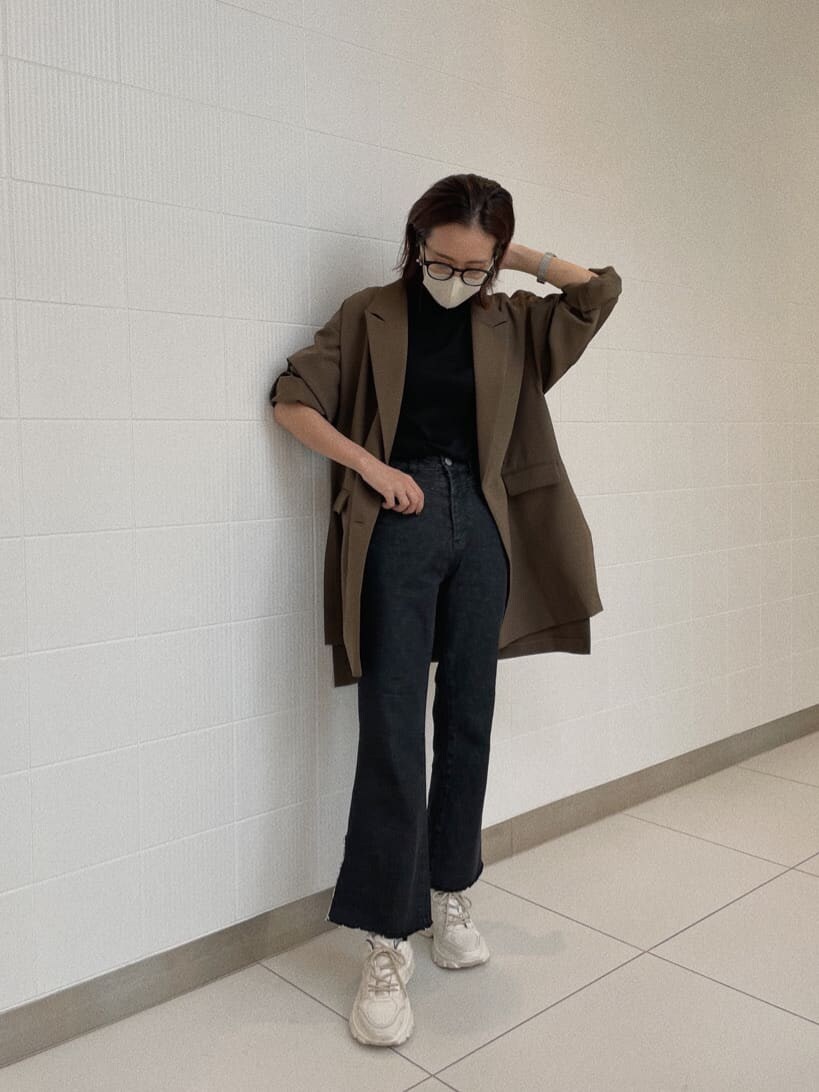 ベージュ系のテーラードジャケット、ブラック系のニット/セーター、ブラック系のデニムパンツを着用したレディースの秋コーディネートの8枚目の写真