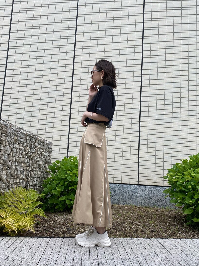 ベージュ系のスカート、ブラック系のTシャツ/カットソーを着用したレディースの春コーディネートの3枚目の写真