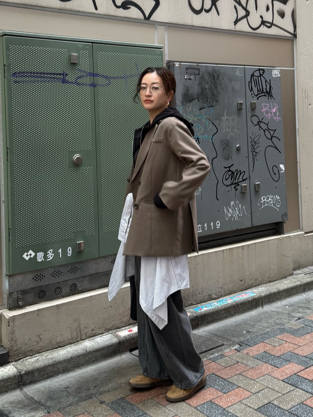 ブラック系のデニムパンツ、ベージュ系のテーラードジャケット、ブラック系のパーカーを着用したレディースの春コーディネートの4枚目の写真