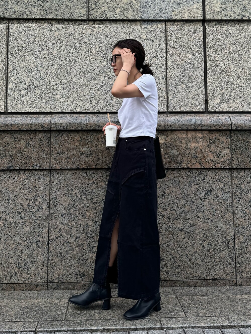 ブラック系のデニムスカート、ブラック系のブーツを着用したレディースの夏コーディネートの3枚目の写真