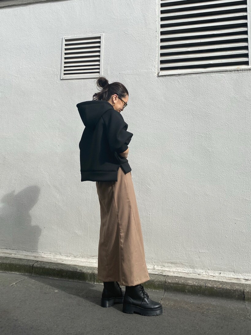 ブラック系のブーツ、ブラック系のパーカー、ブラウン系のスカートを着用したレディースの秋コーディネートの2枚目の写真