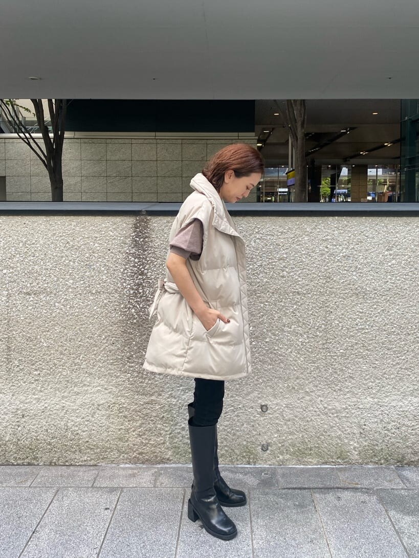 ブラック系のデニムパンツ、ベージュ系のニット/セーター、ホワイト系のダウンベストを着用したレディースの秋コーディネートの4枚目の写真