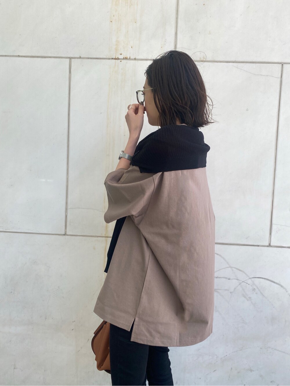 ブラック系のニット/セーター、ベージュ系のTシャツ/カットソー、ブラック系のデニムパンツを着用したレディースの春コーディネートの4枚目の写真