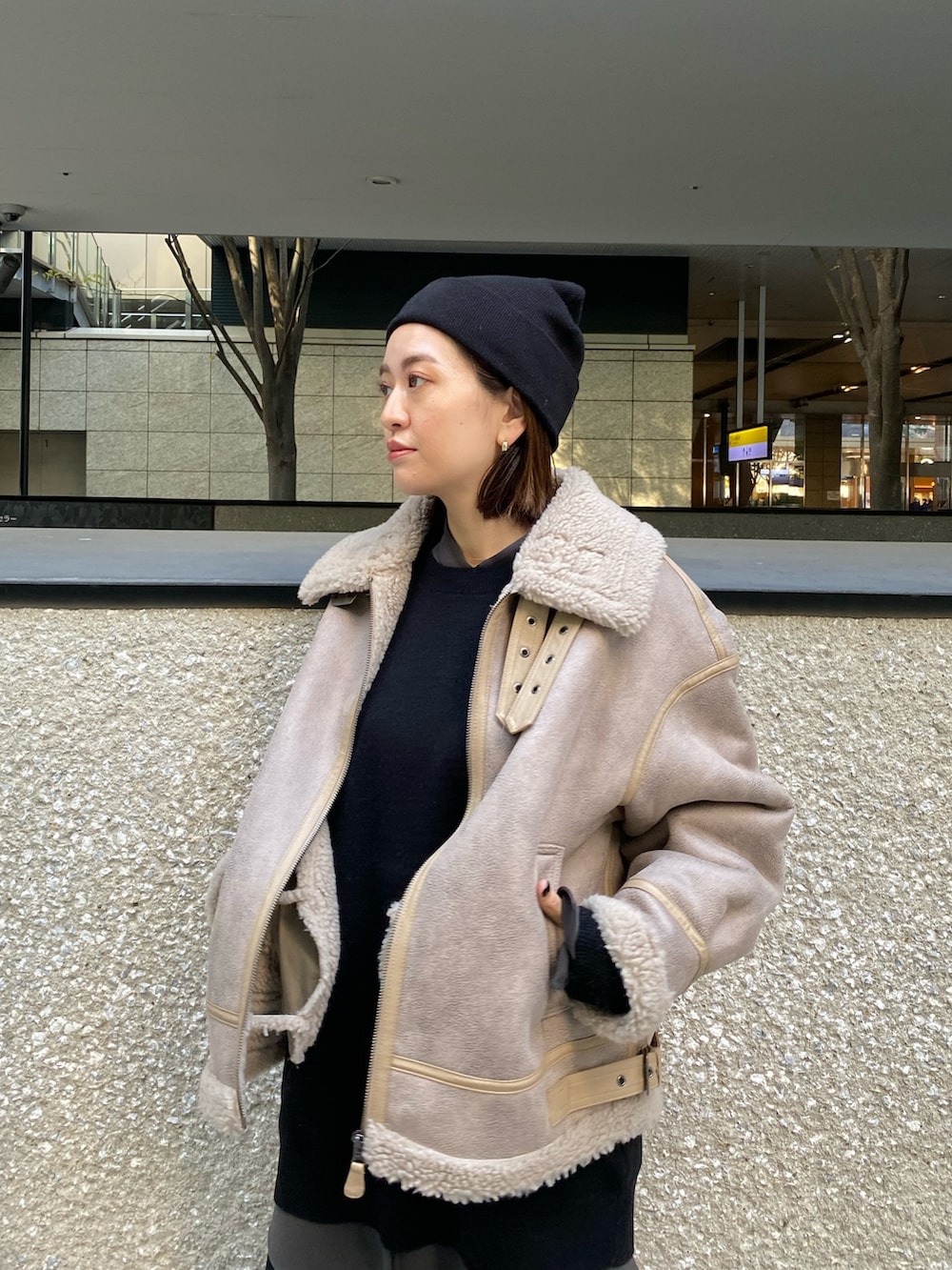 ベージュ系のムートンコート、ブラック系のニット/セーター、ブラック系のブーツを着用したレディースの秋コーディネートの8枚目の写真