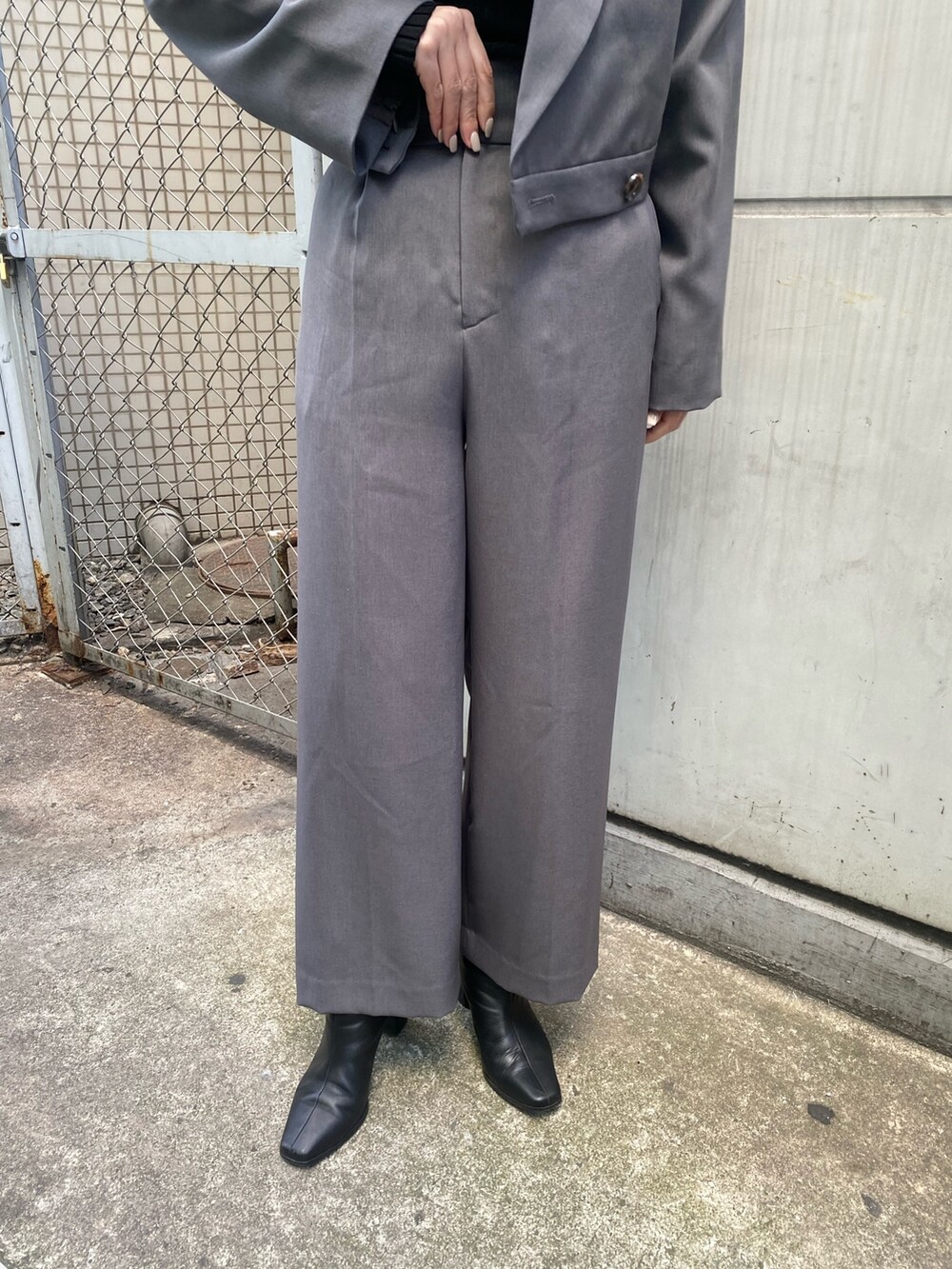 グレー系のテーラードジャケット、ブラック系のニット/セーター、グレー系のスラックスを着用したレディースの冬コーディネートの5枚目の写真