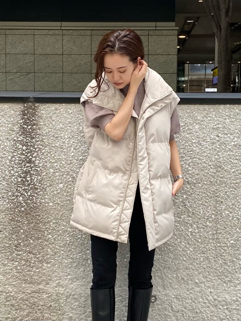 ブラック系のデニムパンツ、ベージュ系のニット/セーター、ホワイト系のダウンベストを着用したレディースの秋コーディネートの6枚目の写真