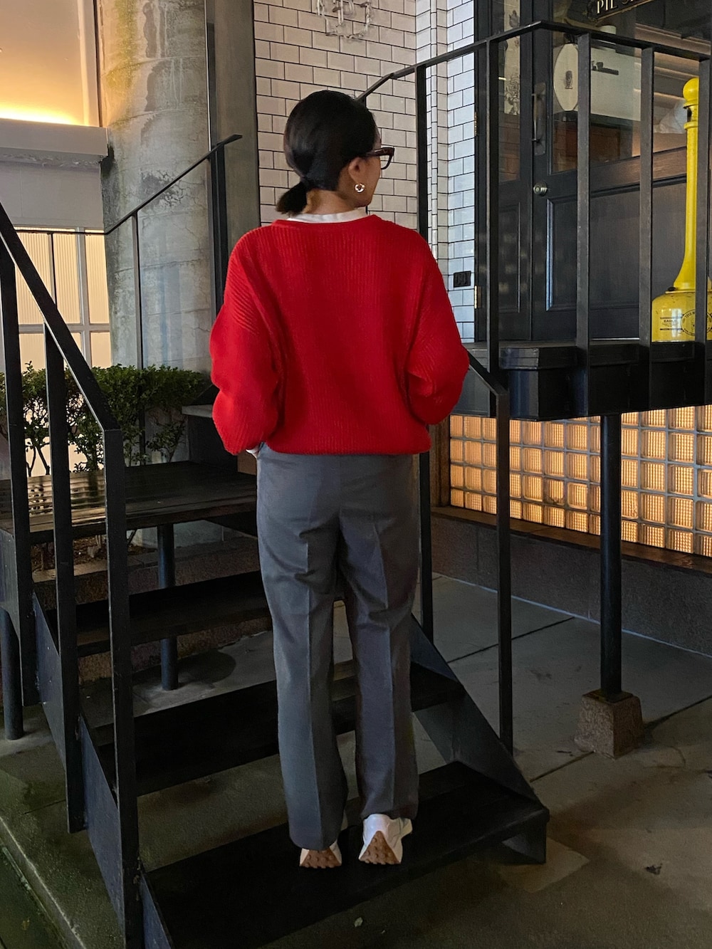 グレー系のスラックス、レッド系のニット/セーターを着用したレディースの秋コーディネートの4枚目の写真