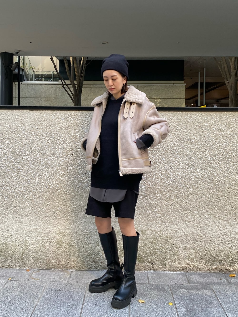 ベージュ系のムートンコート、ブラック系のニット/セーター、ブラック系のブーツを着用したレディースの秋コーディネートの3枚目の写真