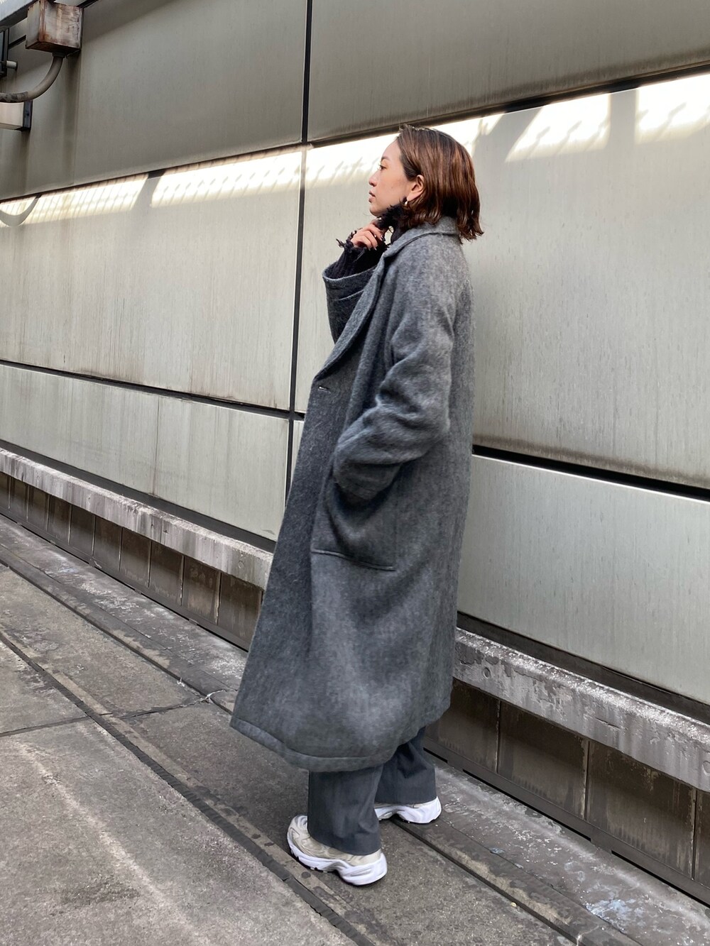 グレー系のチェスターコート、グレー系のニット/セーターを着用したレディースの秋コーディネートの3枚目の写真