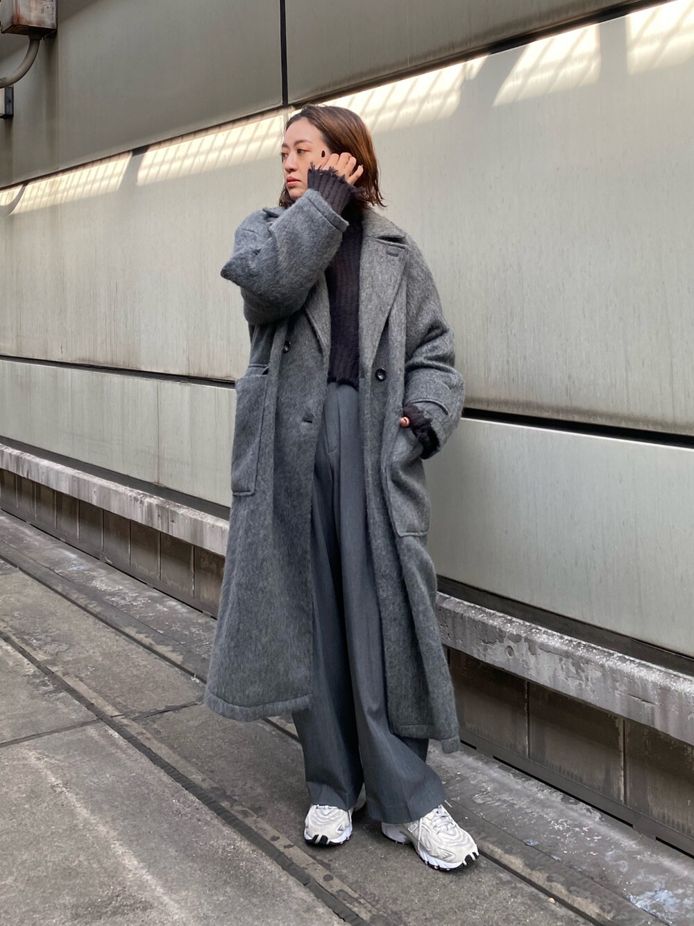 グレー系のチェスターコート、グレー系のニット/セーターを着用したレディースの秋コーディネートの2枚目の写真