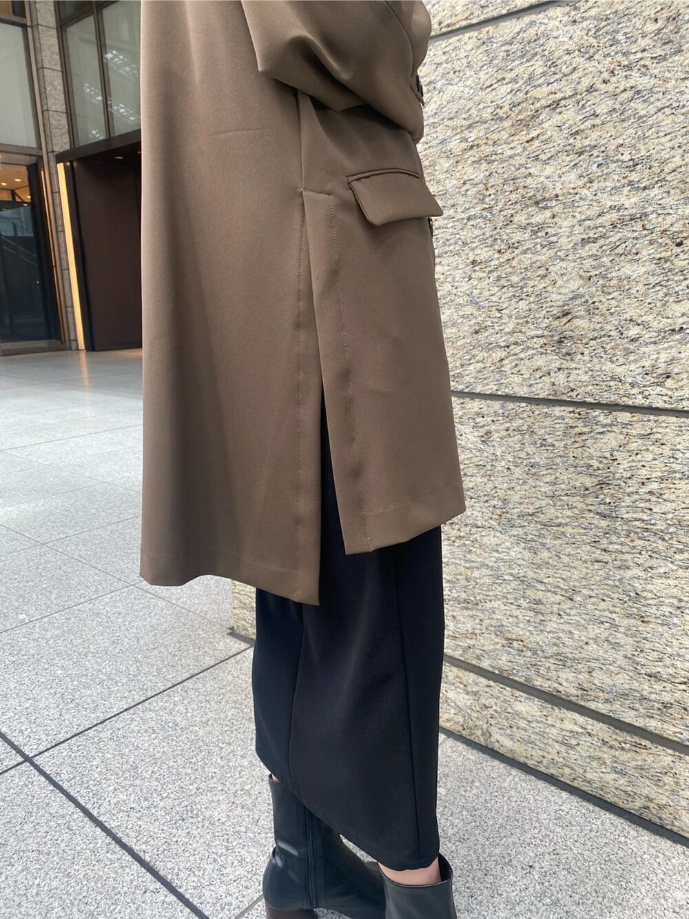 ブラック系のニット/セーター、ブラック系のスカート、ベージュ系のテーラードジャケットを着用したレディースの秋コーディネートの6枚目の写真