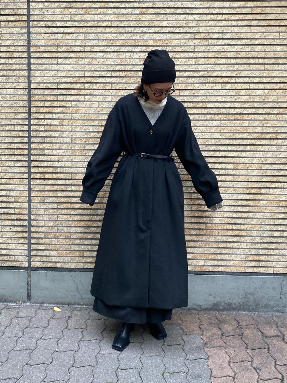 ブラック系のノーカラーコート、ブラック系のブーツを着用したレディースの冬コーディネートの3枚目の写真