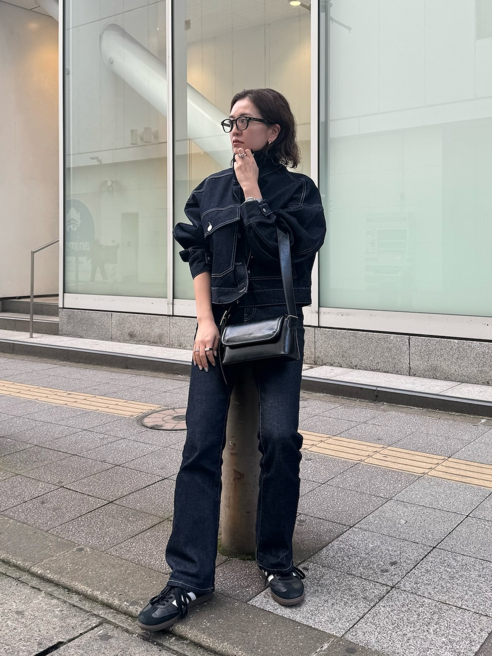 ブルー系のデニムジャケット、ブラック系のショルダーバッグ、ブルー系のデニムパンツを着用したレディースの春コーディネートの5枚目の写真