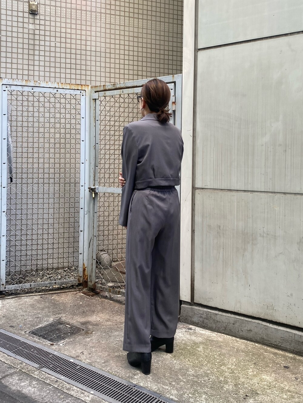 グレー系のテーラードジャケット、ブラック系のニット/セーター、グレー系のスラックスを着用したレディースの冬コーディネートの3枚目の写真