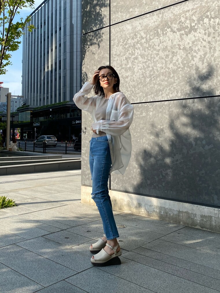 ホワイト系のサンダル、ブルー系のデニムパンツ、ベージュ系のニット/セーターを着用したレディースの春コーディネートの3枚目の写真