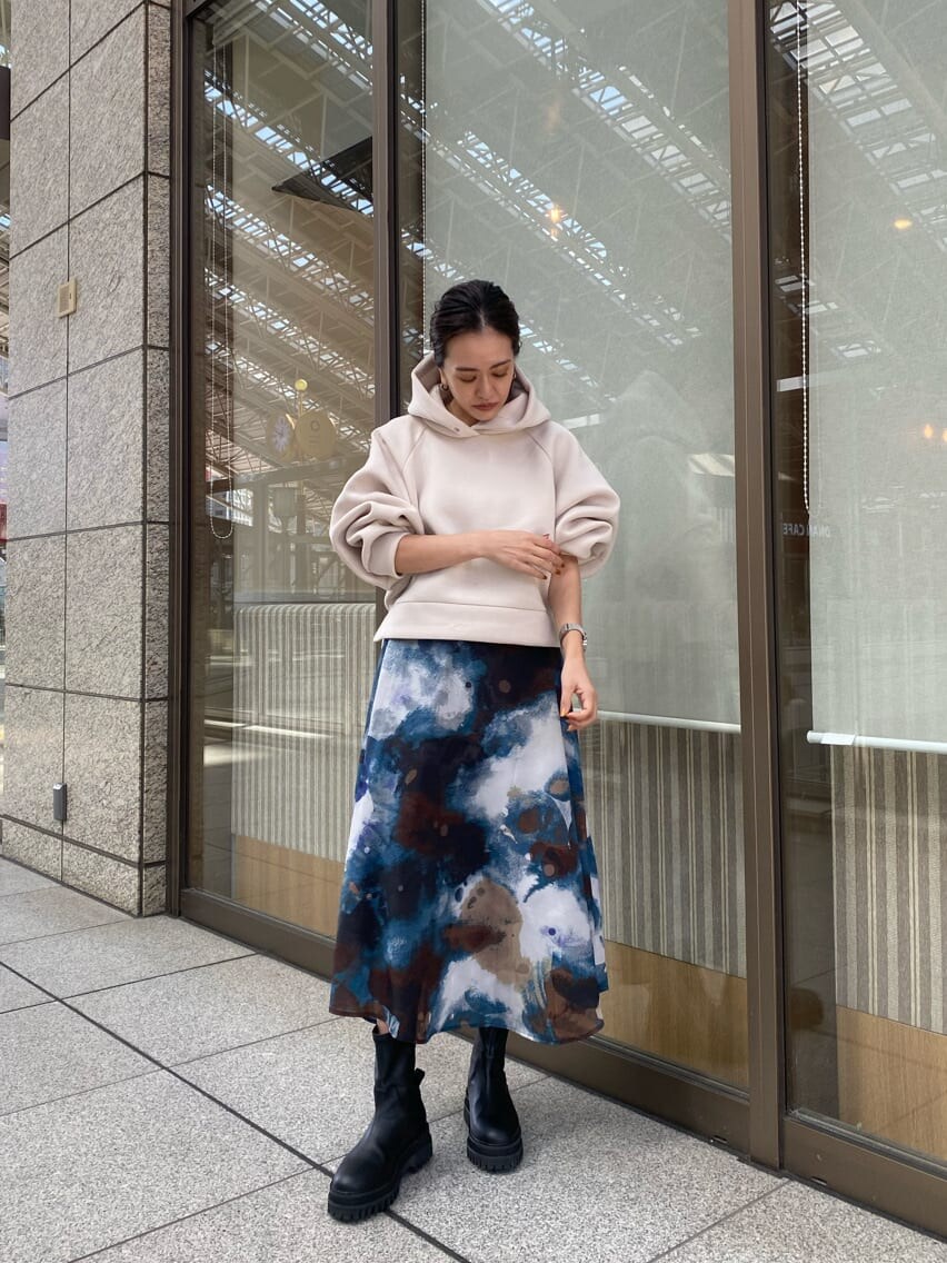 ブルー系のスカート、ブラック系のブーツ、ホワイト系のパーカーを着用したレディースの秋コーディネートの2枚目の写真