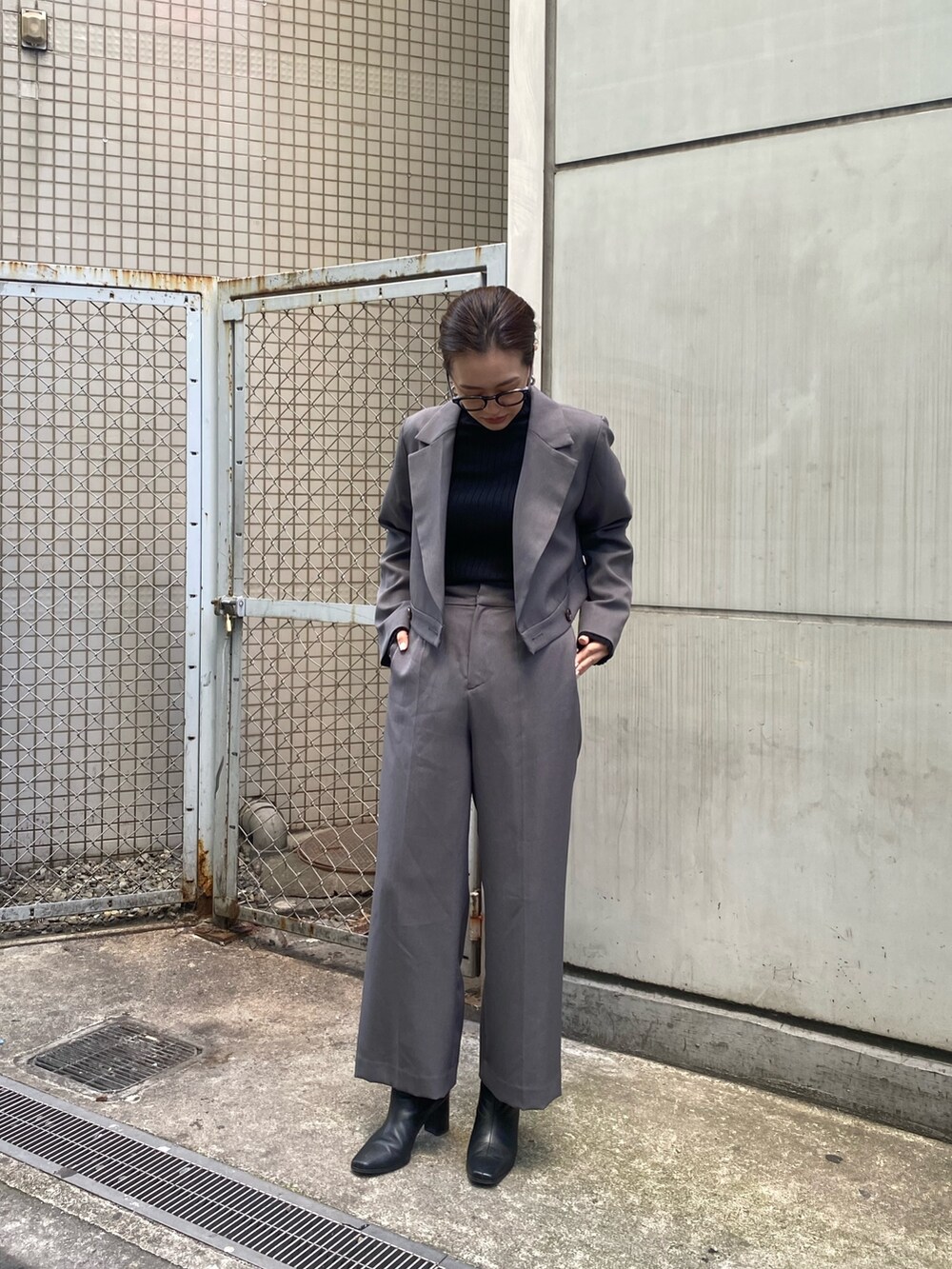グレー系のテーラードジャケット、ブラック系のニット/セーター、グレー系のスラックスを着用したレディースの冬コーディネートの4枚目の写真