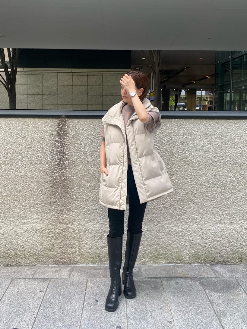 ブラック系のデニムパンツ、ベージュ系のニット/セーター、ホワイト系のダウンベストを着用したレディースの秋コーディネートの2枚目の写真