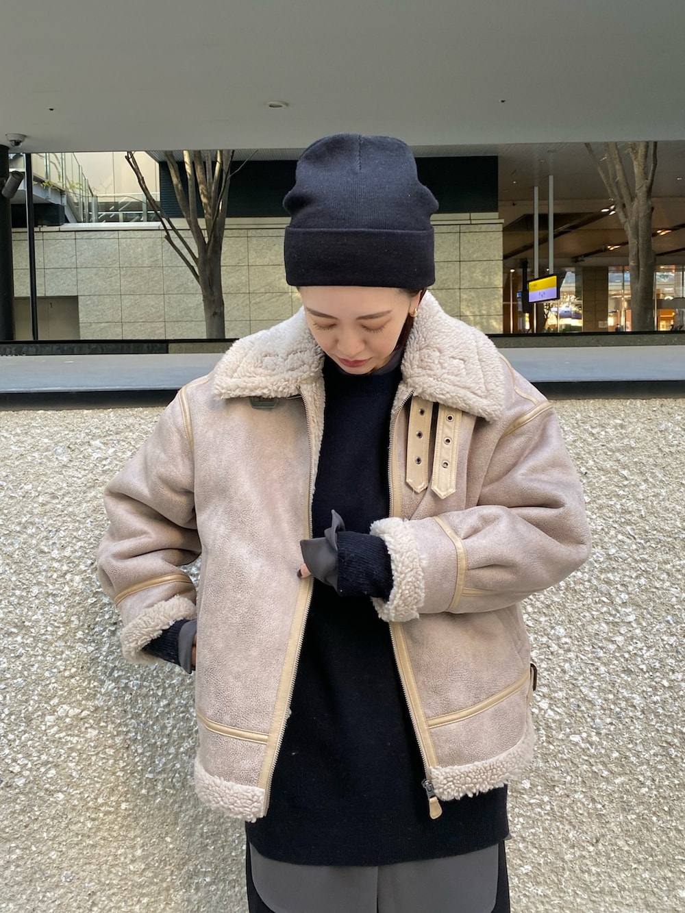 ベージュ系のムートンコート、ブラック系のニット/セーター、ブラック系のブーツを着用したレディースの秋コーディネートの6枚目の写真