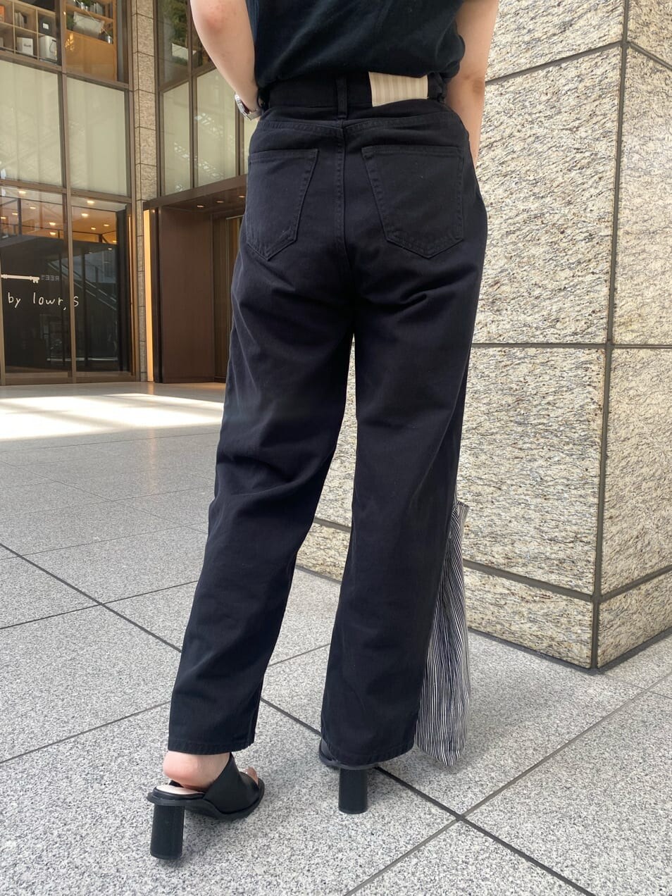 ブラック系のデニムパンツ、ブラック系のサンダルを着用したレディースの春コーディネートの7枚目の写真