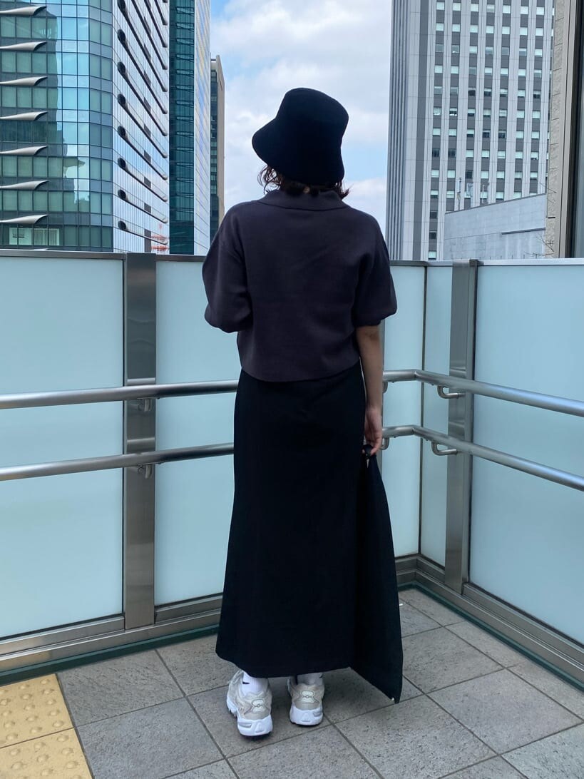 ブラック系のスカート、グレー系のニット/セーター、ブラック系のハットを着用したレディースの春コーディネートの4枚目の写真