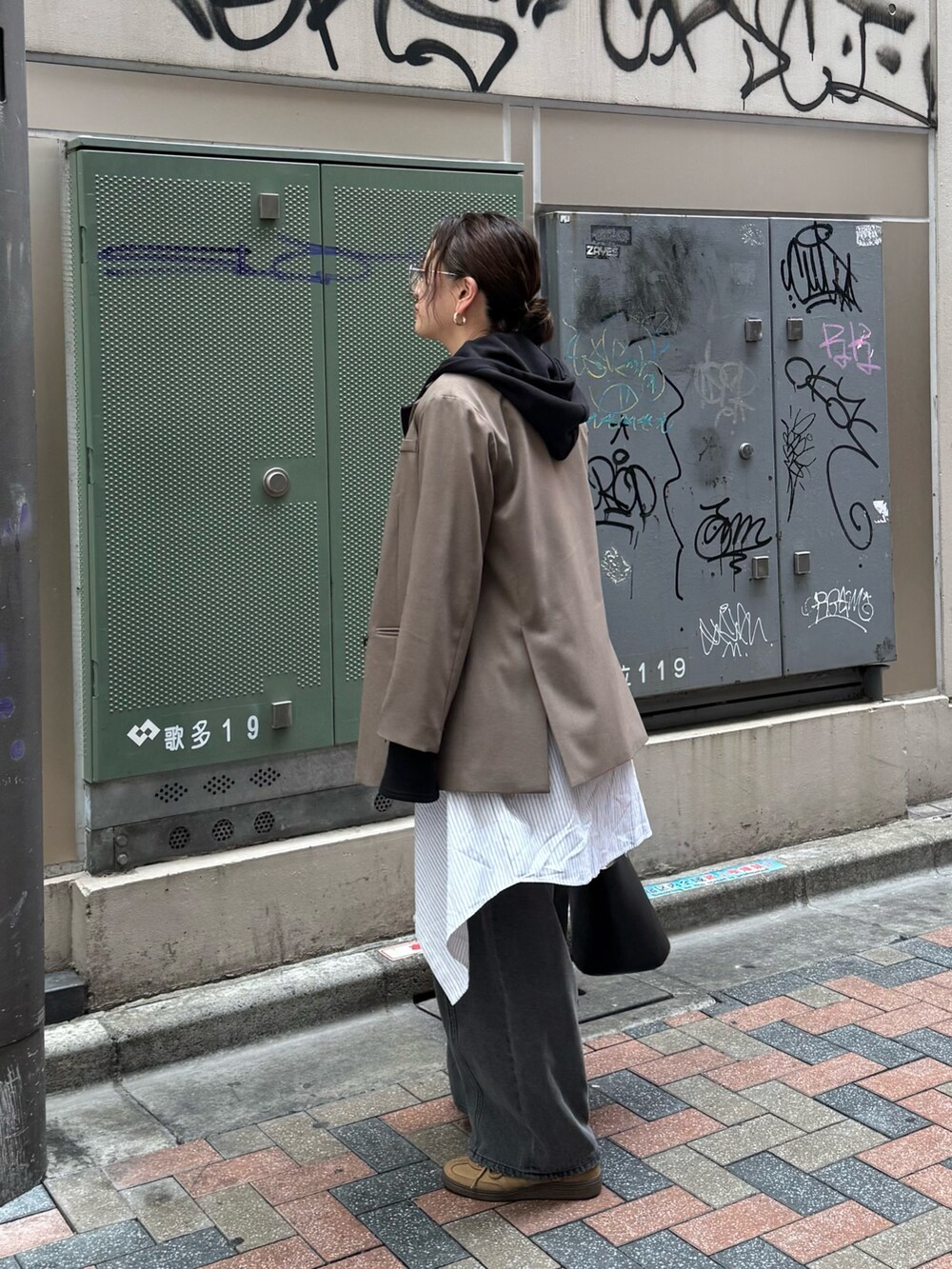 ブラック系のデニムパンツ、ベージュ系のテーラードジャケット、ブラック系のパーカーを着用したレディースの春コーディネートの2枚目の写真
