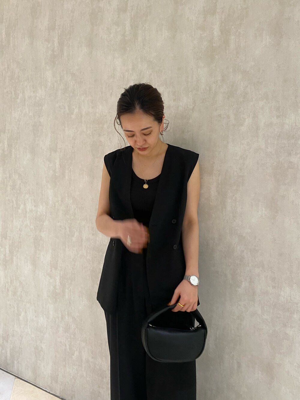 ブラック系のテーラードジャケット、ブラック系のスラックス、ブラック系のハンドバッグを着用したレディースの春コーディネートの6枚目の写真