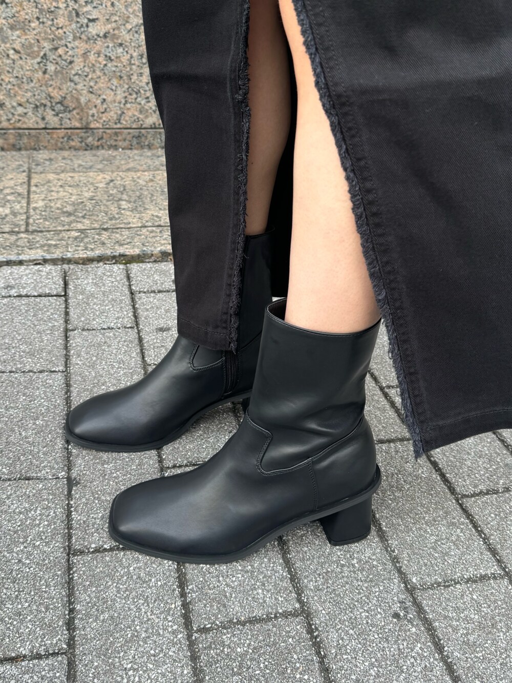 ブラック系のデニムスカート、ブラック系のブーツを着用したレディースの夏コーディネートの6枚目の写真