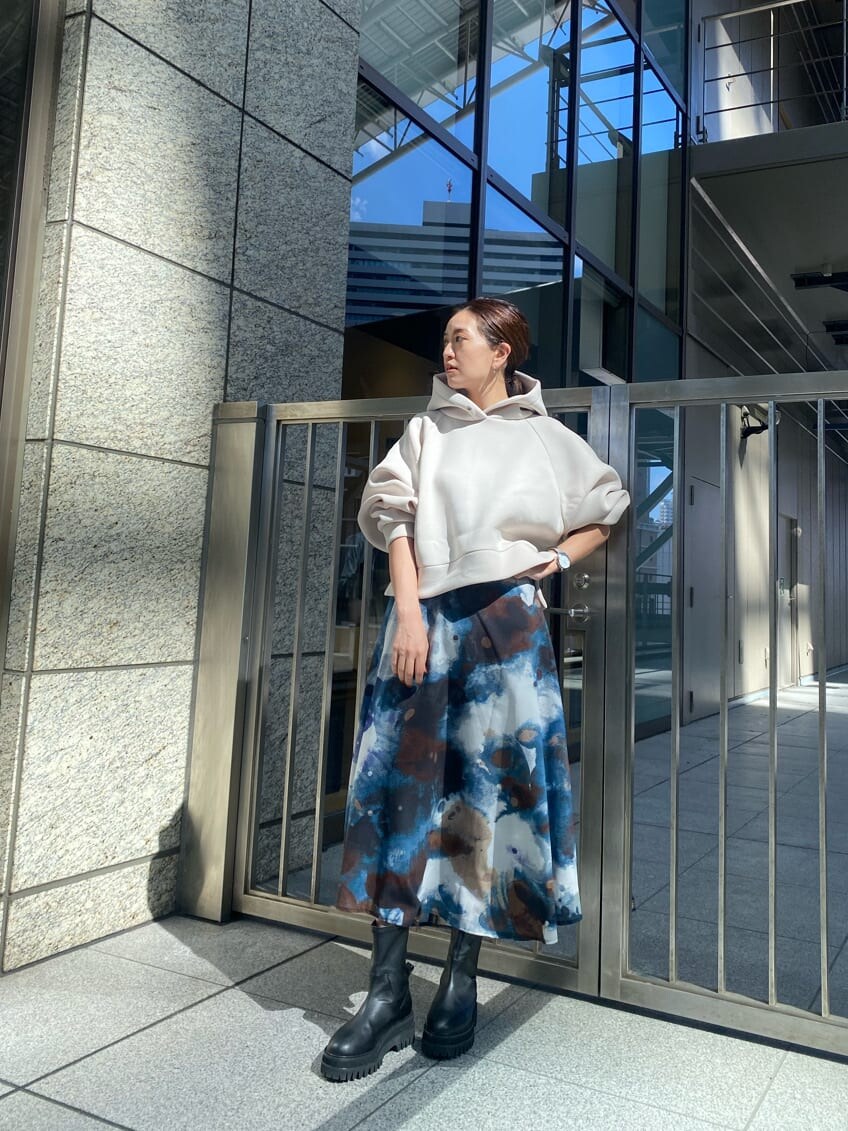 ブルー系のスカート、ブラック系のブーツ、ホワイト系のパーカーを着用したレディースの秋コーディネートの3枚目の写真